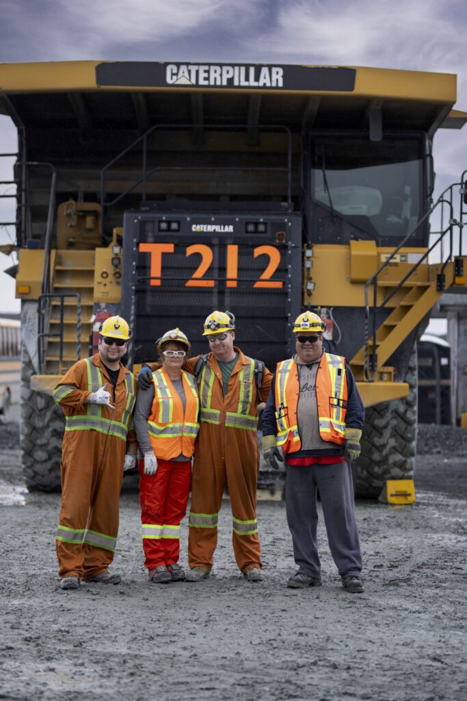 Miners in front of a massive earth-moving truck at Lac des Iles Mine, Thunder Bay