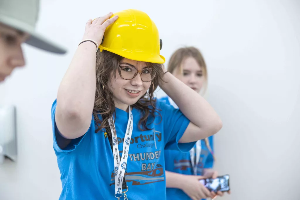 A young student trying on a helmet during the Mine Opportunity Challenge