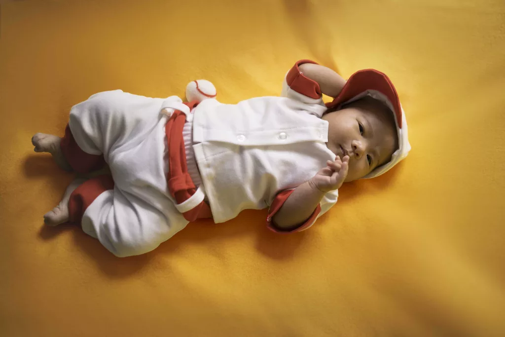 Baby liam wearing a baseball outfit on a yellow photography backdrop
