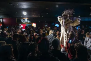 Event photography from the Derelicte Fashion Odyssey, held at Black Pirate Pub and hosted by the Definitely Superior Art Gallery, showing a model in wearable art with a fur coat and large wolf head on stage in Thunder Bay.