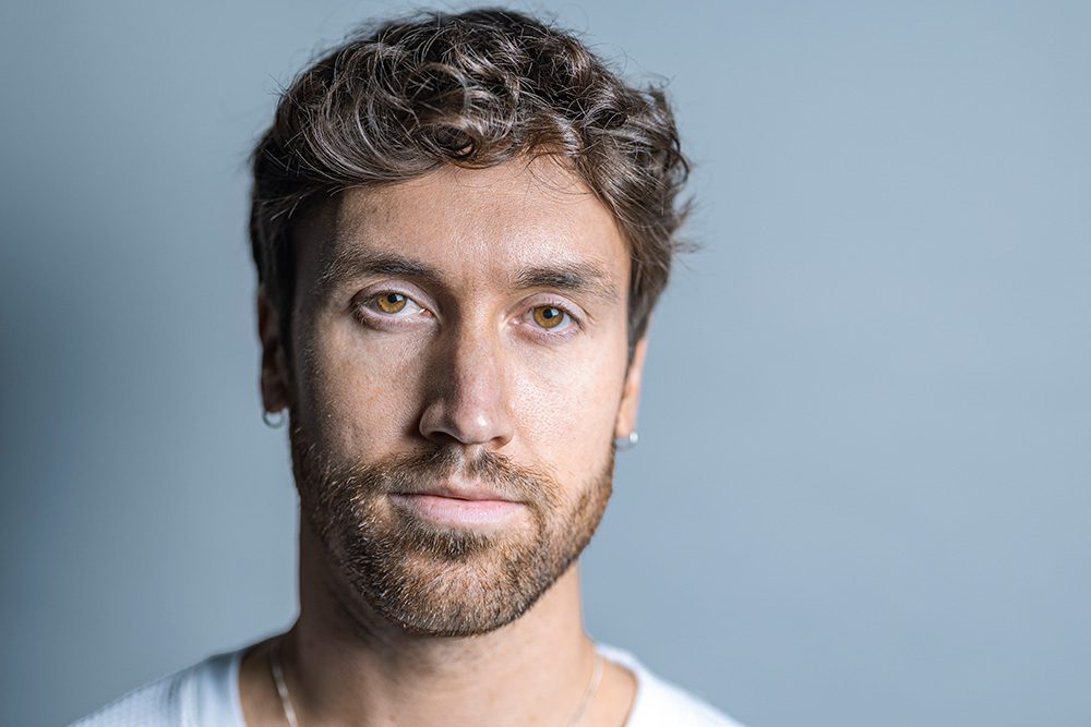 Extreme close-up of Josh’s face, shot in high contrast with bright light that overexposes his skin in a stylized, artistic way.