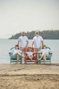 Audrey and her full family sitting in colorful chairs on the beach at their Lake Superior cottage, all wearing white shirts and khaki pants during a family photoshoot.