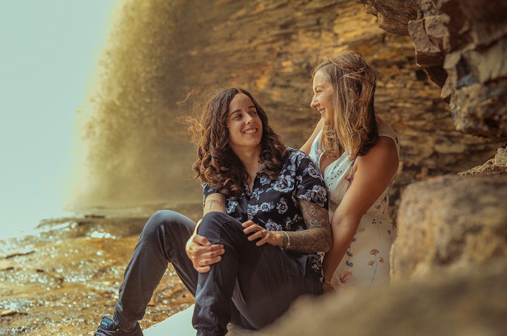 Jess and Sam lovingly looking at each other in front of a cascading waterfall at Wolf River Falls in Thunder Bay.