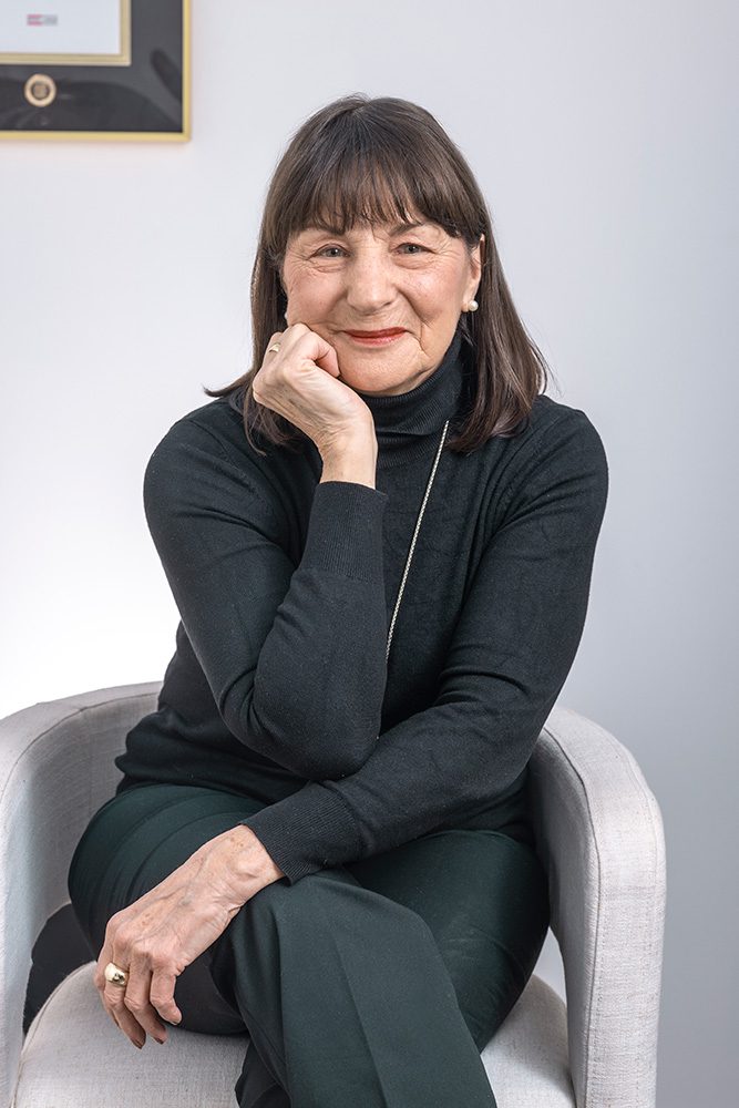 Audrey from Royal LePage sitting in a high-top chair with her hand resting on her face, wearing a confident, professional expression.