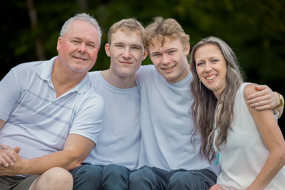 A close-up portrait of Sarah, her husband, and their two sons smiling together during their beach photo session—captured with Photography Gift Cards in Thunder Bay.