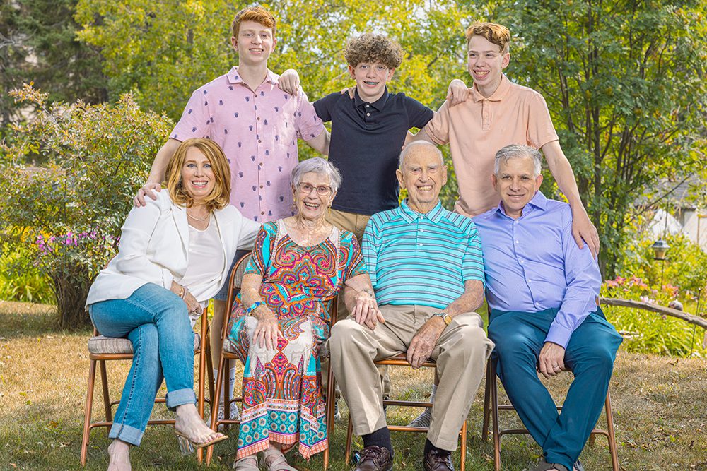 Norma, her husband, and their daughter’s family smiling together during a summer family portrait session in Thunder Bay.