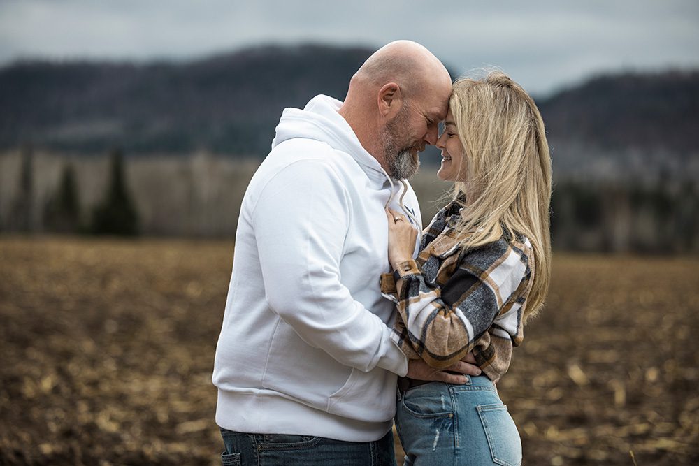 Jess and her husband smiling with foreheads together in front of a mountain range