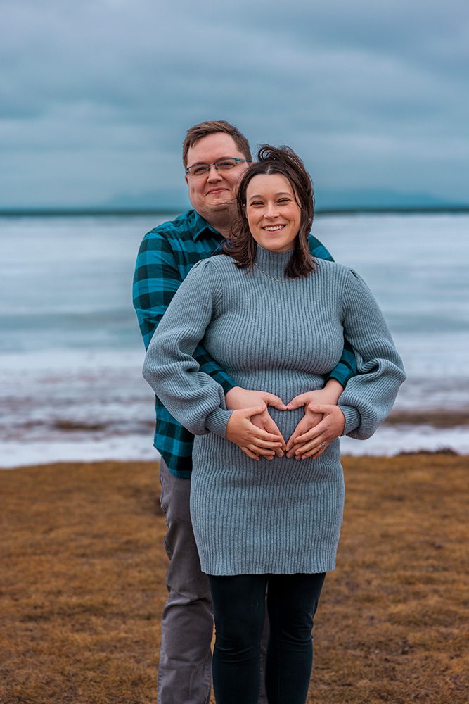 Close-up of Sophie and Jeff making a heart shape with their hands on Sophie’s baby bump during their maternity shoot at Chippawa Park in Thunder Bay, Ontario.