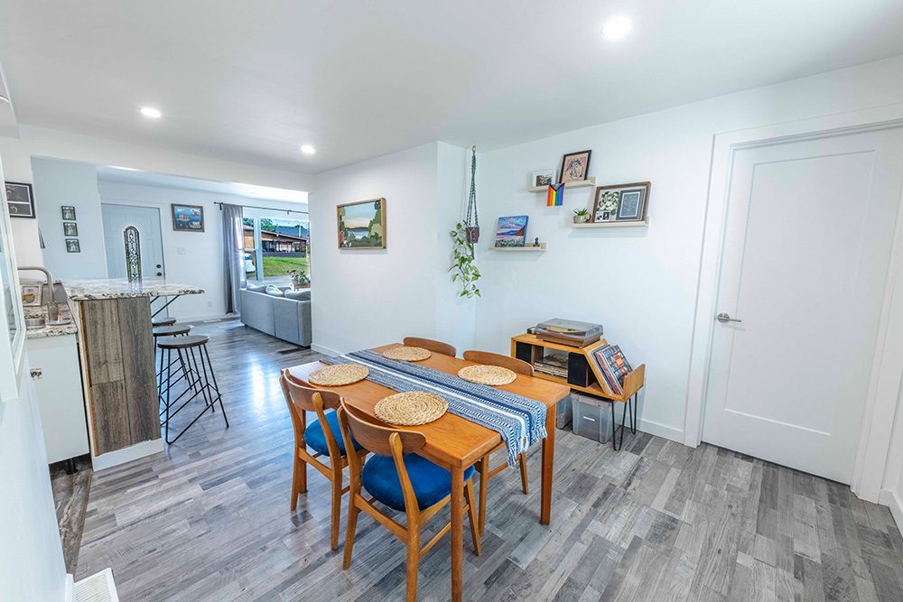 Modern dining room with mid-century wooden table, blue chairs, and open concept kitchen