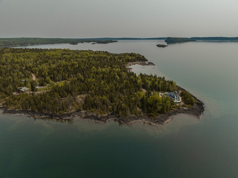 Aerial view of forested peninsula with waterfront homes on pristine lake with multiple islands