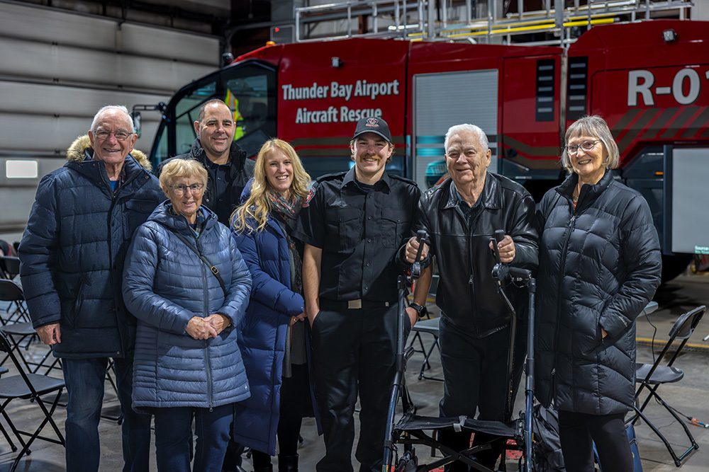 Corporate milestone photography of airport operations team with graduates and rescue vehicle
