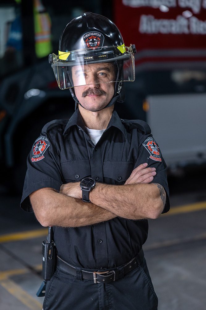 Corporate milestone photography environmental portrait of airport firefighter with helmet