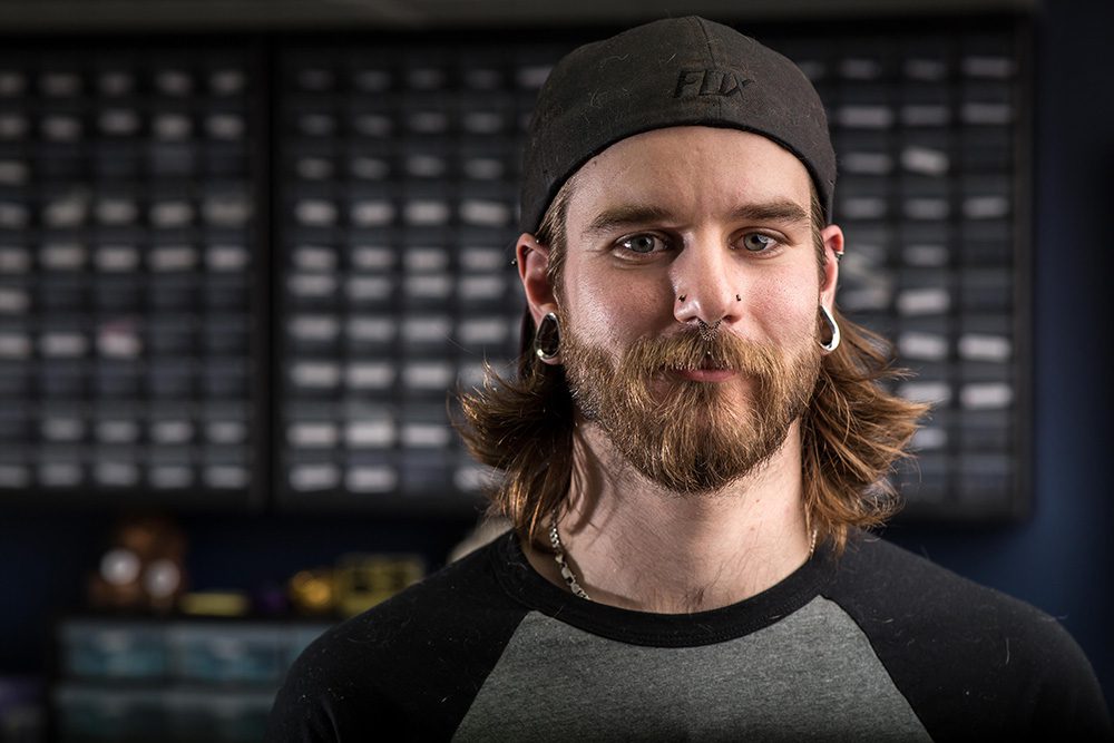 Portrait of a tattoo artist inside a tattoo studio with piercing supplies in the background.