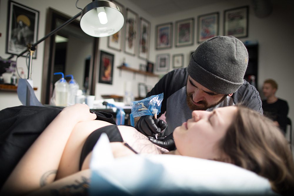 Tattoo artist using professional equipment during chest tattoo session at Identity Tattoo and Piercing