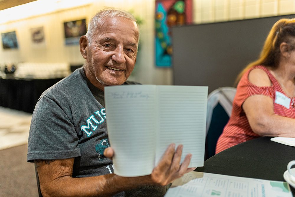 Senior male participant reviewing event materials with coffee at workshop