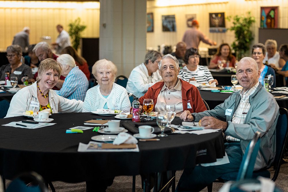 Group of senior attendees seated at round tables during business seminar