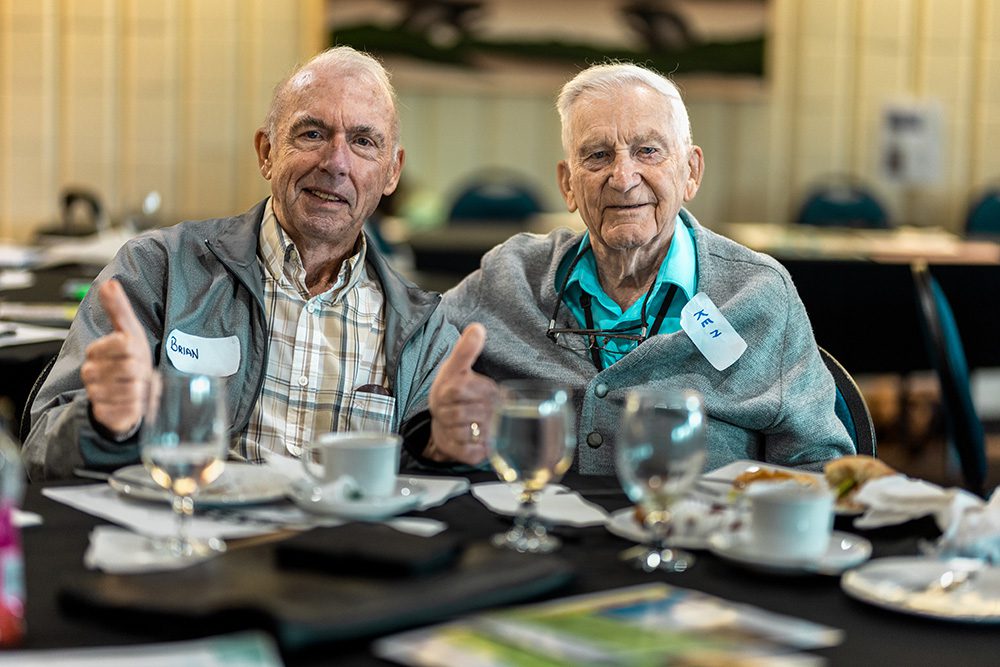 Two senior men smiling together at round table during business workshop