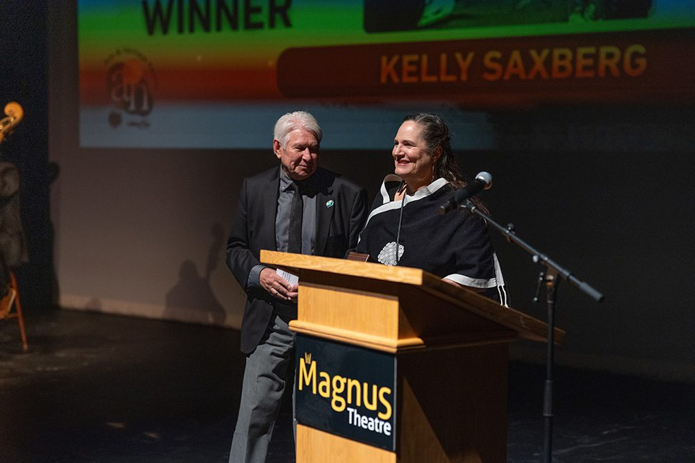 Woman in black and white athletic jacket receiving award at podium on stage