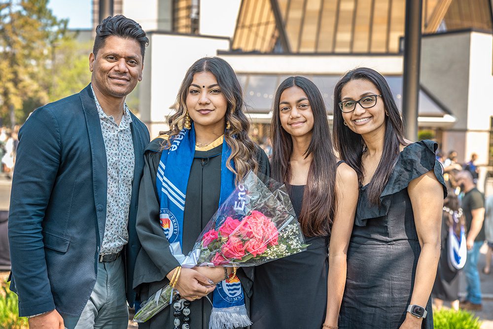 University graduation photography outdoor family portrait with graduate holding flowers and diploma