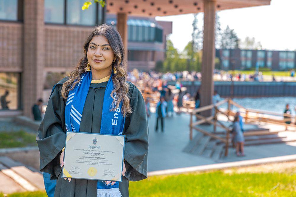 University graduation photography individual portrait of graduate holding diploma on campus