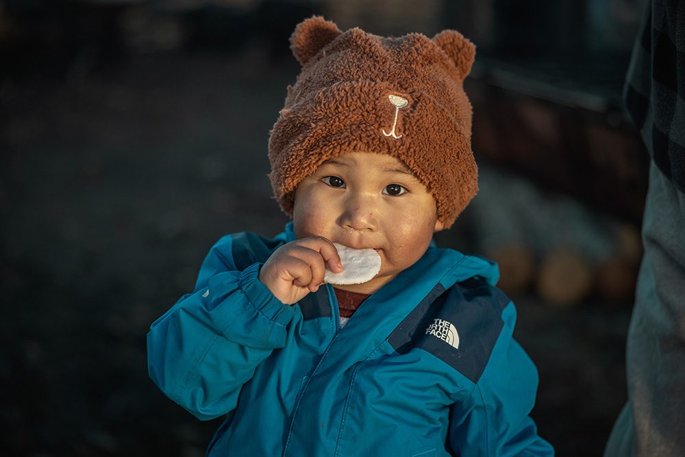 Young child eating during the Moose Festival at North Caribou Lake