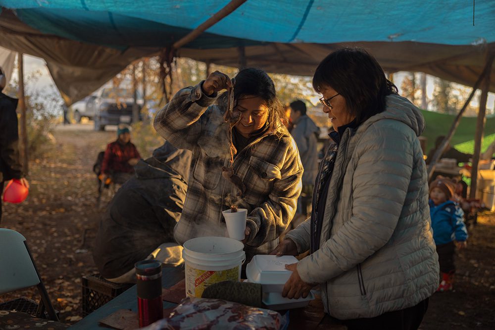 Community members serving hot food under a tarp during the Moose Festival