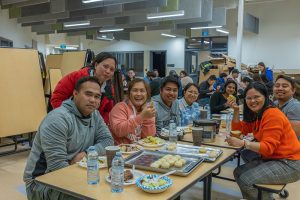 Group of community members sharing a meal indoors during the Moose Festival