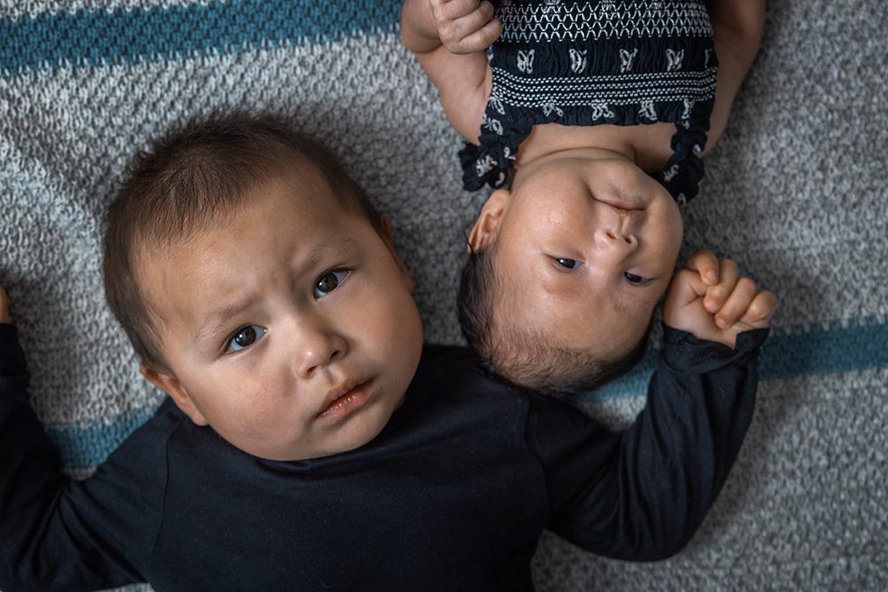 Toddler and newborn baby lying together overhead sibling portrait