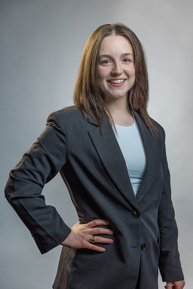 Confident medical student professional headshot hand on hip gray studio background