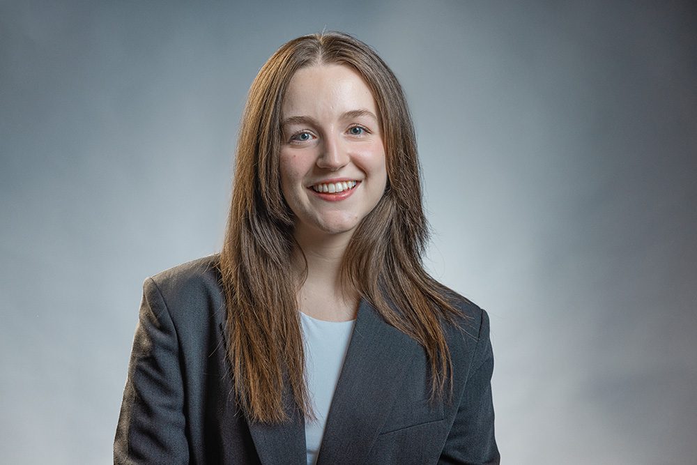 Approachable medical student portrait in navy blazer on neutral gray background