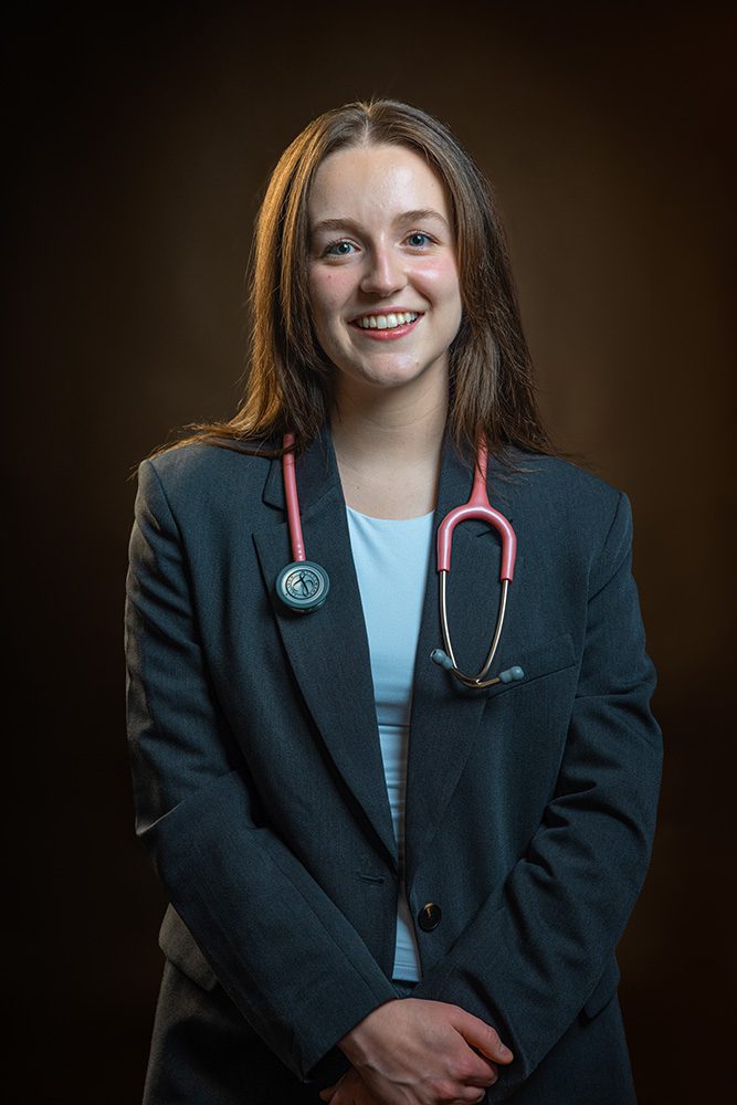 Smiling medical student in professional blazer with stethoscope warm studio portrait