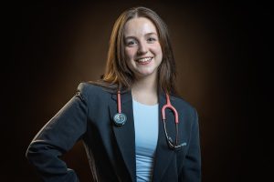 Confident medical student portrait with hand on hip wearing stethoscope and navy suit