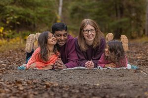 Family of four lying on blanket autumn path happy smiling portrait