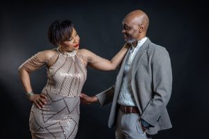 Couple posing together during a glamorous anniversary photoshoot with a dark background