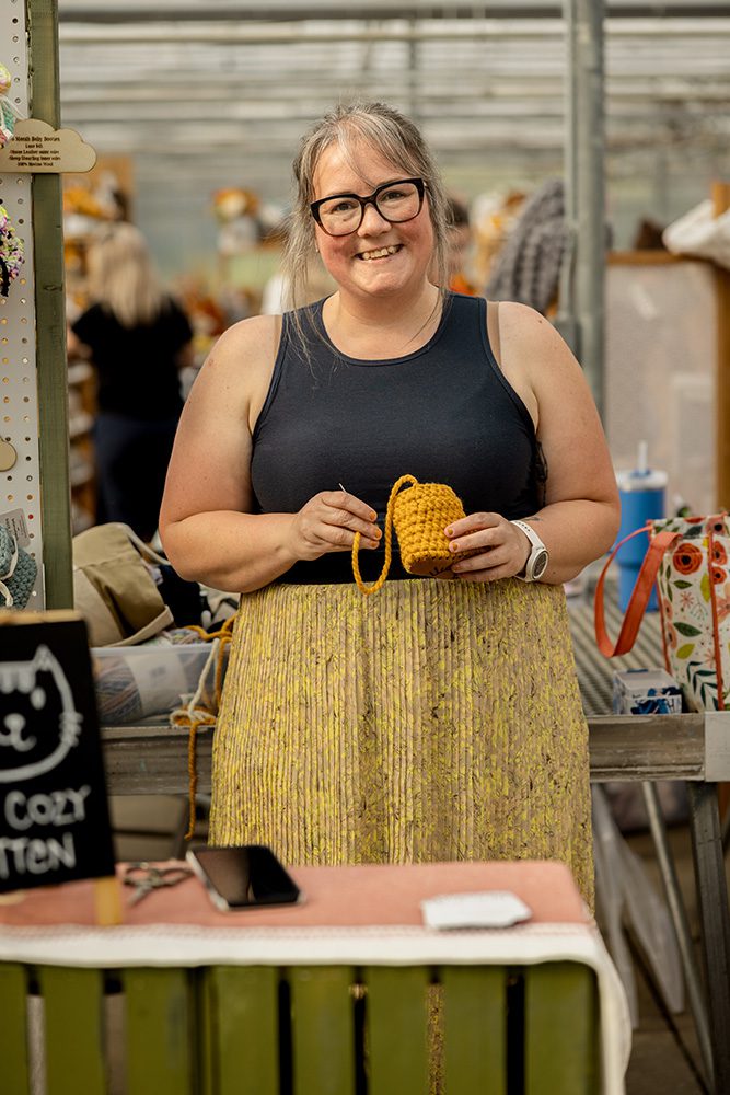 Small business advertising photos showing craft vendor crocheting at market booth