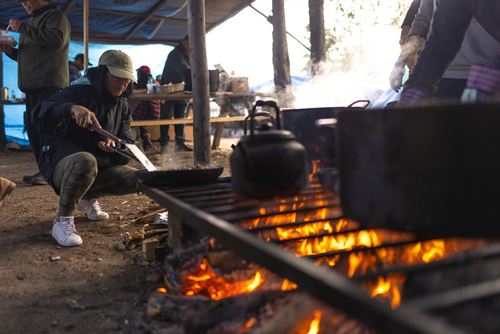 Community member cooking over an open fire during the Moose Festival at North Caribou Lake