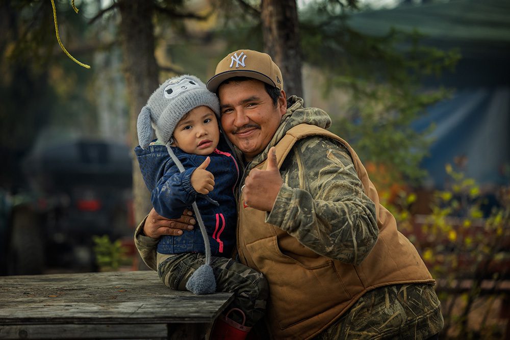 Adult holding a young child during the Moose Festival at North Caribou Lake