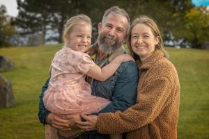 Close-up of family embracing with daughter arms around parents during outdoor portrait