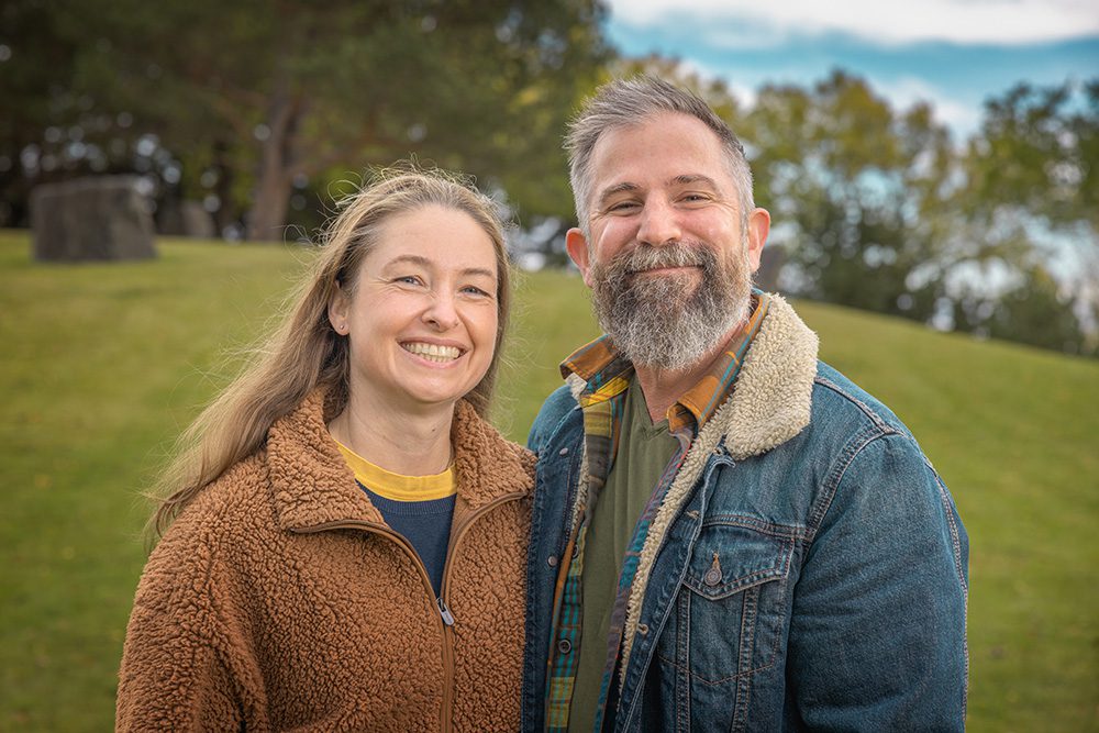 Couple smiling together during outdoor portrait session with autumn trees background