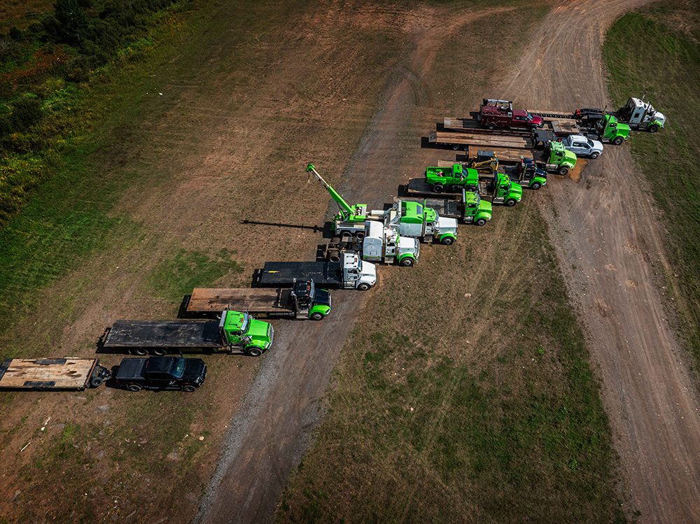 Professional trucking company photography aerial view of Hartley towing fleet with green trucks at company yard