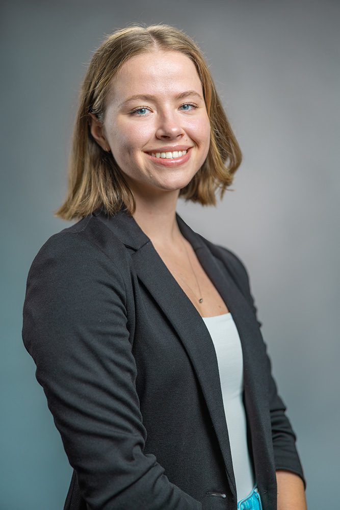 Smiling professional woman headshot black blazer light background approachable