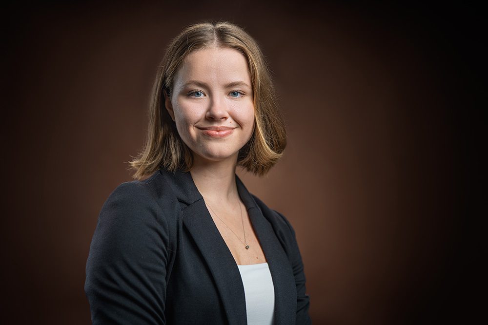 Business headshot woman black blazer warm background professional photo