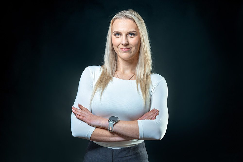 Corporate headshot woman white long-sleeve top dark background professional