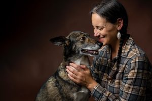 Woman looking lovingly at her dog in close-up studio portrait with warm brown background