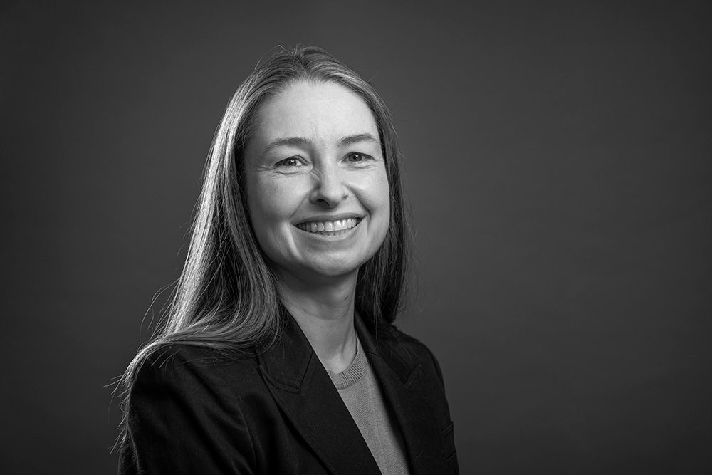 Black and white portrait of professional woman in dark suit jacket smiling warmly