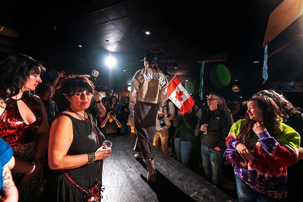 Model in Canada jacket holding flag walking runway with audience