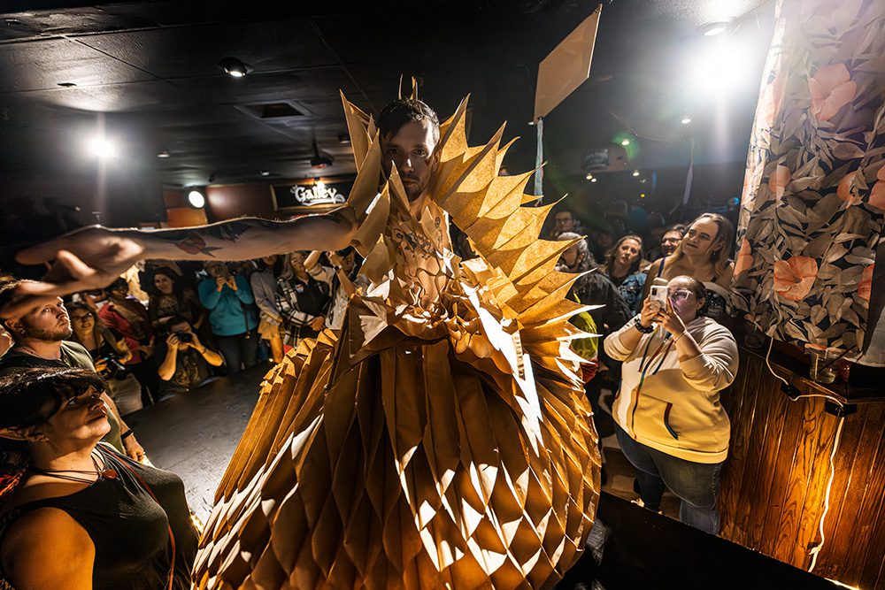 Model in golden angular paper costume with dramatic collar on runway