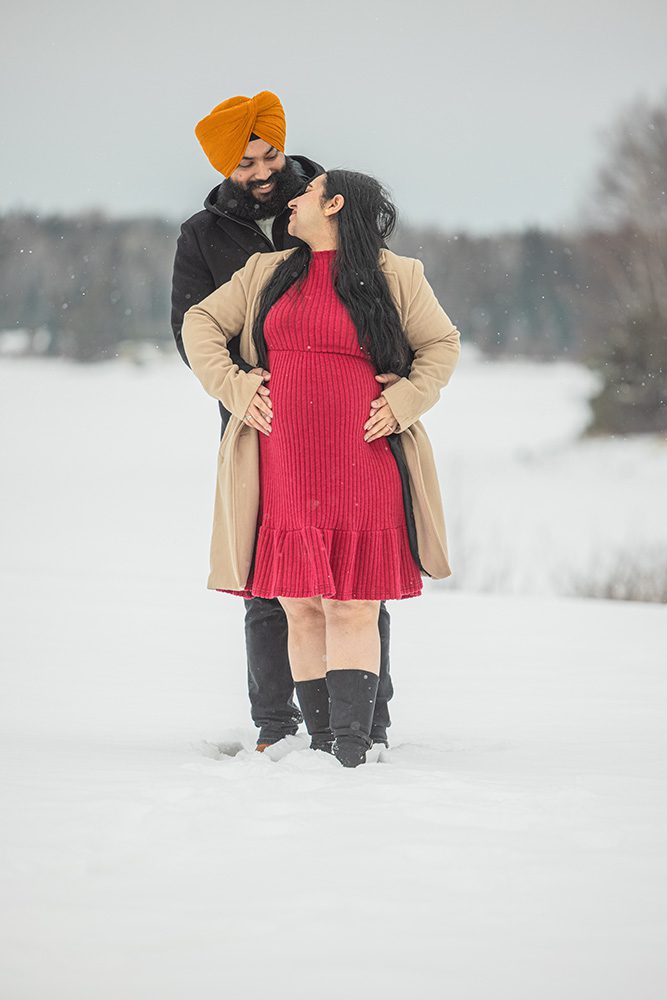 Expecting couple looking at each other during snowy winter maternity session