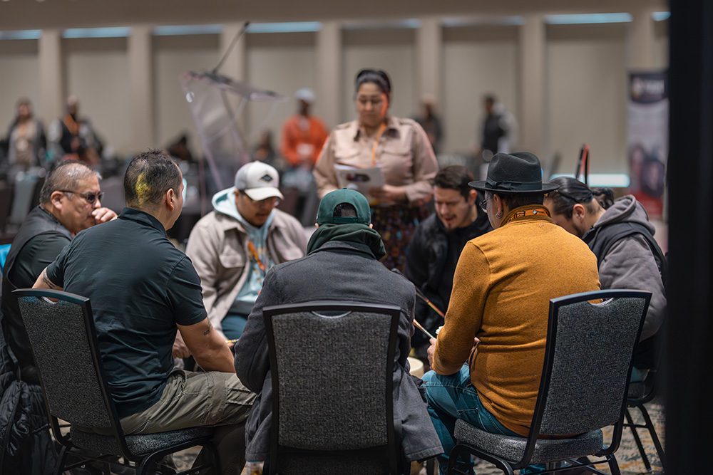 Small group of men in discussion circle at conference with facilitator standing