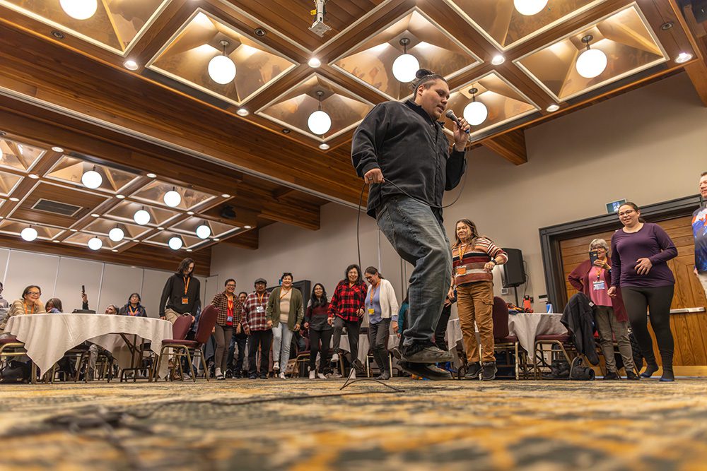 Indigenous man speaking passionately at conference with microphone from low angle